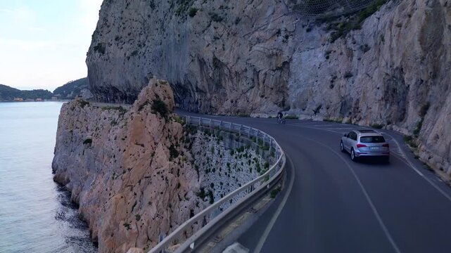 aerial shot. Travel by the sea. Serpentine asphalt road under the cliff. Tourism. Stone Cave of counterfeiters in Capo Noli in Liguria, Italy 19.08.2025