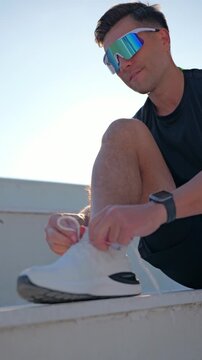 A man puts on running shoes at dawn, prepares for a cardio workout.