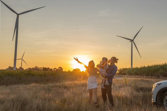 Family with son walking on field on wind farm. Happy Family and son playing at the Wind turbines generating electricity. Family time together.