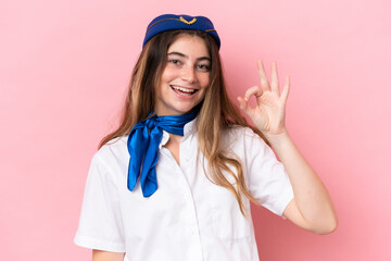 Airplane stewardess caucasian woman isolated on pink background showing ok sign with fingers