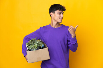 Man making a move while picking up a box full of things pointing to the side to present a product