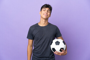 Young football player man over isolated purple background laughing