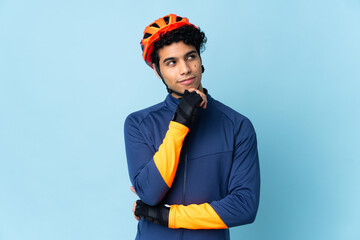Venezuelan cyclist man isolated on blue background and looking up
