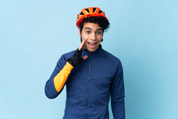 Venezuelan cyclist man isolated on blue background with surprise and shocked facial expression