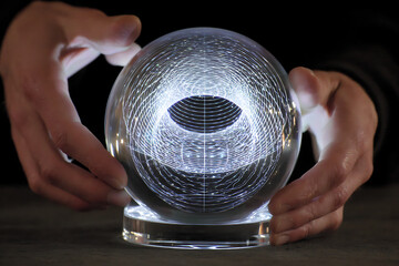 Hands holding a crystal ball with glowing geometric patterns, fortune telling concept
