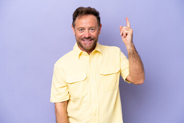 Fototapeta premium Middle age caucasian man isolated on purple background happy and pointing up
