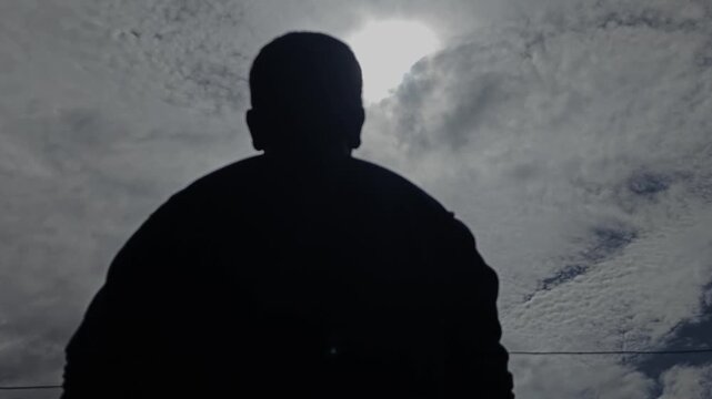 silhouette of a man looking up at the sky with the sunlight from the clouds, slow motion, 4K, Bright Sun light, Nature and Mental health, B-Roll Footage Inspirational and Motivational background.