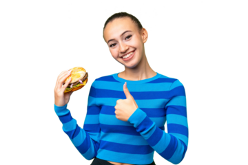 Young Arab woman holding a burger over isolated background giving a thumbs up gesture