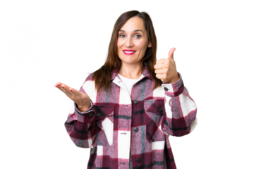Middle age woman over isolated chroma key background holding copyspace imaginary on the palm to insert an ad and with thumbs up