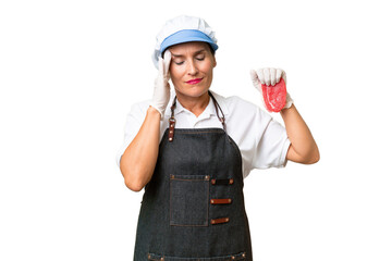Butcher woman wearing an apron and serving fresh cut meat over isolated background with headache