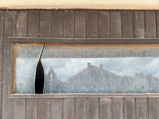 Broken Glass Window in an Old Wooden Garage Door. Signs of neglect, vandalism, or wear and tear....