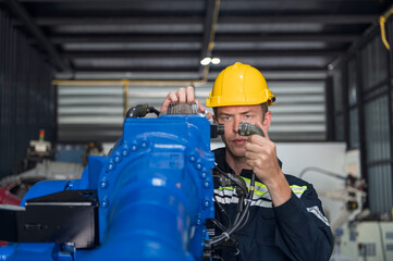 Engineer standing by robotic arm and operating machine in industry factory, technician worker check...