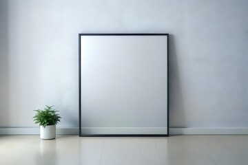 A blank framed mirror leans against a textured wall next to a potted plant