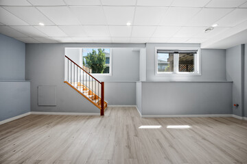 Large, empty room with a staircase and a window