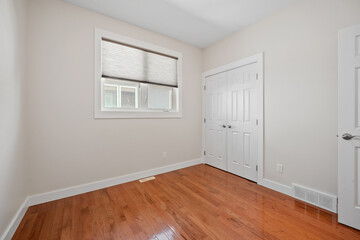 Small, empty bedroom with a wooden floor and a white door