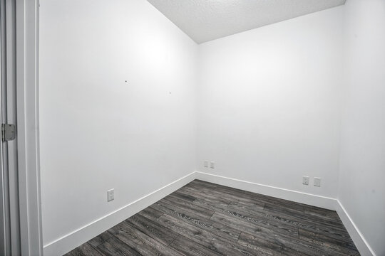 Small, empty room with a white wall and wooden floor