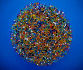 a large, circular cluster of colorful gel beads or water beads placed on a bright blue background.