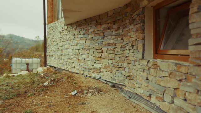 Stone cladding on a building facade, showing layers of natural rock and warm earth tones