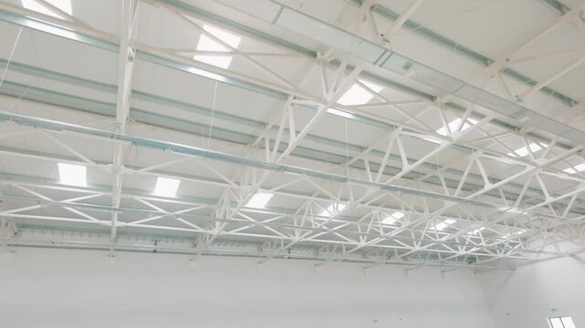 Bright white industrial ceiling with a complex structure of metal trusses and skylights
