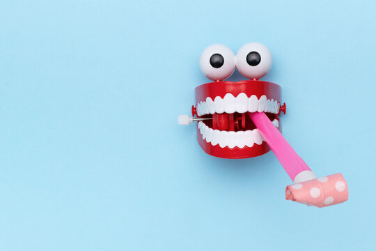 Playful Wind-Up Teeth Toy with Googly Eyes and Candy on Blue Background