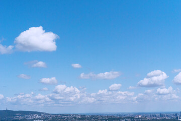 Obraz premium View of Bratislava skyline with lush green landscape and cumulus clouds in blue sky. Ideal for backgrounds, textures, or layouts.