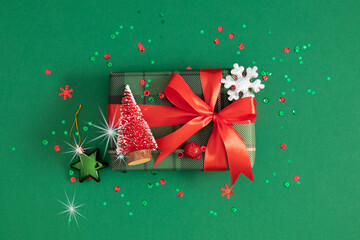 Beautiful Christmas gift in the center of the composition with decorative ornaments. Festive green...
