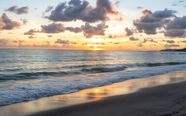 Obraz premium Sunset over the beach and sea with waves and clouds