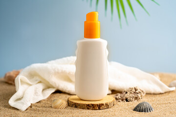 Bright sun care bottle on wood stand with sand, coral, shells, white towel, and palm leaf. Summer vacation scene for skincare branding, SPF mockups, or beach wellness ads