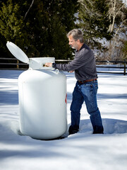 Man tends to a giant prophane tank in winter
