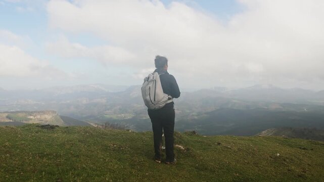 A hiker stands on a grassy hill in Gorbea Natural Park