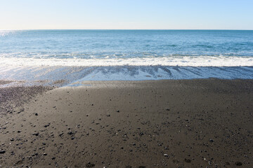 Small waves rolling up at Reynisfjara black sand beach in Iceland