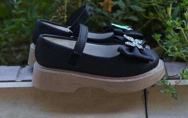 Girls in black shoes with bows are lying on the ground in nature.