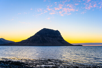 Sun setting behind beautiful Kirkjufell mountain in Grundarfjordur Iceland