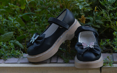 Girls in black shoes with bows are lying on the ground in nature.