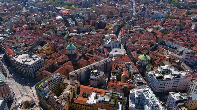 Vivid aerial drone footage showcasing Milan&rsquo;s densely built historic city center, colorful terracotta rooftops, iconic domed churches, lively streets, and classic Italian architecture in Italy.