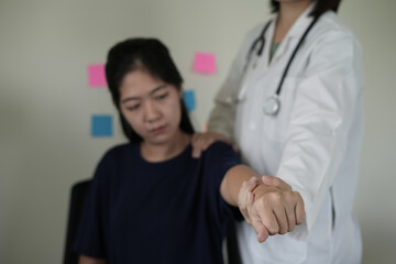 Physiotherapist doing physiotherapy for patient in a hospital room, helps to recover from shoulder pain by moving the arm, body and muscles. The concept of treating illnesses with physical therapy.