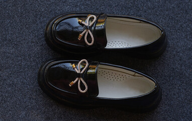 Girls' shiny black shoes on the carpet