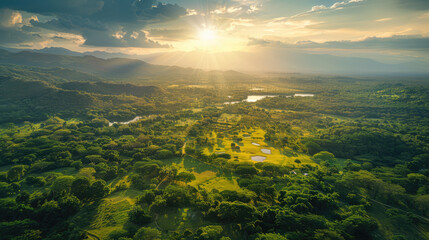 Scenic landscape with a golf course, lush forest, and mountains under a radiant sunset. Serene and picturesque.