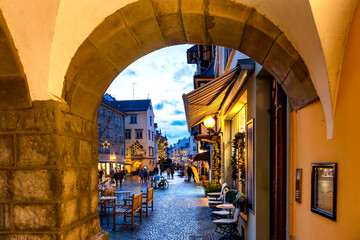 Charming view through an old stone archway into the festively decorated pedestrian zone of Lindau's old town, Bodensee, Germany