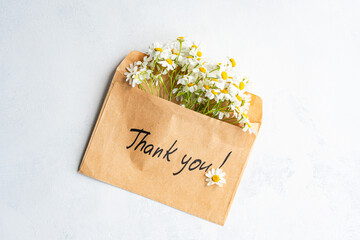 Envelope with daisies and thank you message on white