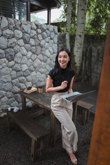 Fototapeta premium Young Asian Freelancer Working Remotely From Garden With Laptop