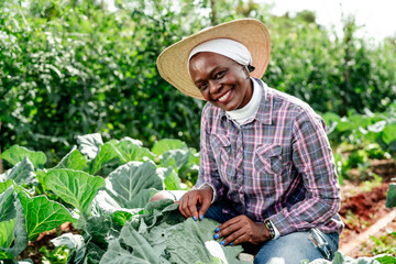 Happy Farmer in Hat Tending to Lush Vegetable Garden