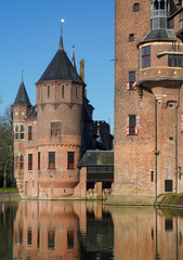 Fototapeta premium Castle de Haar's iconic tower stands tall as a charming historic bridge gracefully connects two grand sections of this magnificent Dutch estate. 