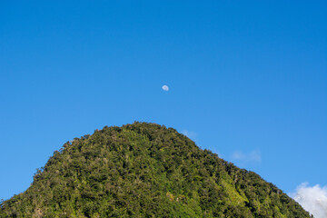 Mountain Peak with Moon in Clear Blue Sky