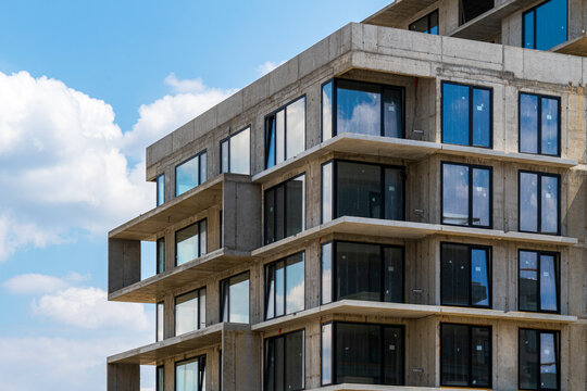 Residential building under construction with exposed concrete and glass windows