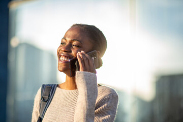 Joyful African American woman having phone conversation in sunlight