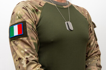 Fototapeta premium A soldier in camouflage with an Italian flag patch and army badges around his neck.