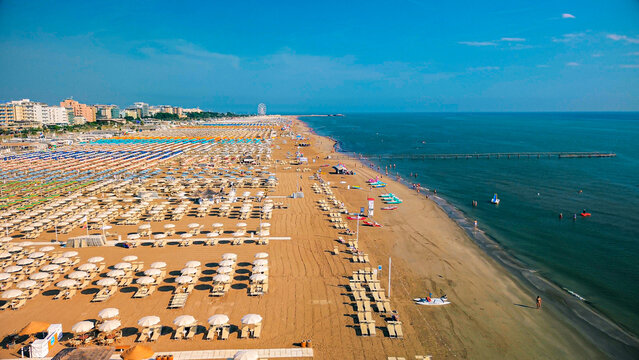 Aerial view of large equipped sandy beaches. Umbrellas and sun loungers for vacationers by the sea. Vacation on the Adriatic Sea. Ferris wheel. Traveling on Europe. Vacation in Italy Rimini 21.08.2025
