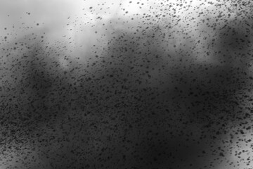 A grayscale depiction of a dark, cloudy formation with scattered particles in the foreground