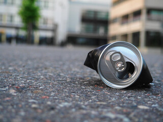 A Discarded Aluminum Beverage Container Lying on the Pavement Outside a Modern Building